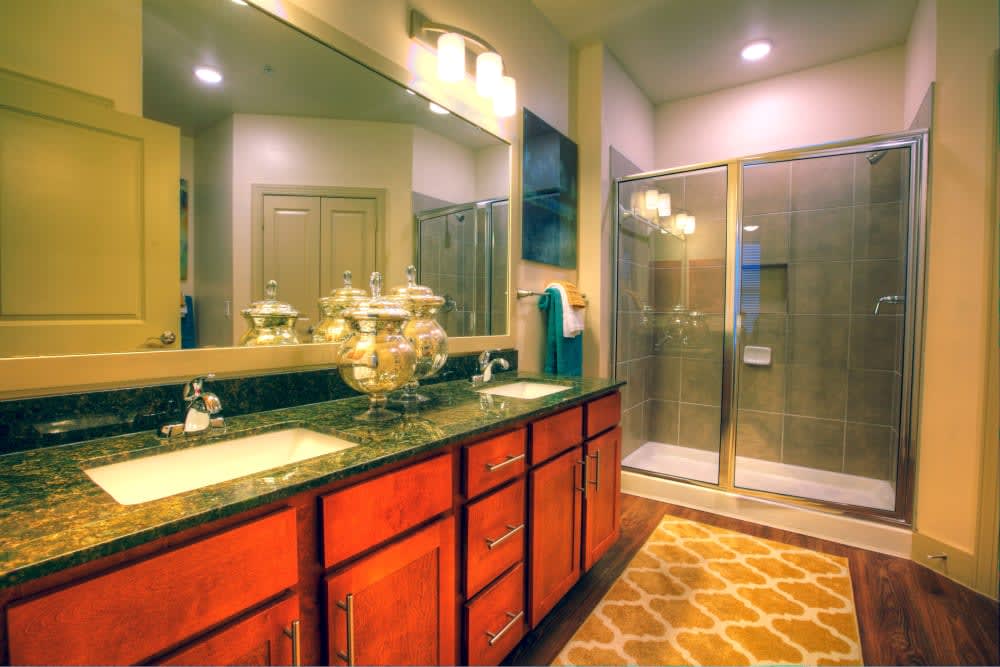 A modern bathroom with a large vanity, spacious shower, and warm lighting.