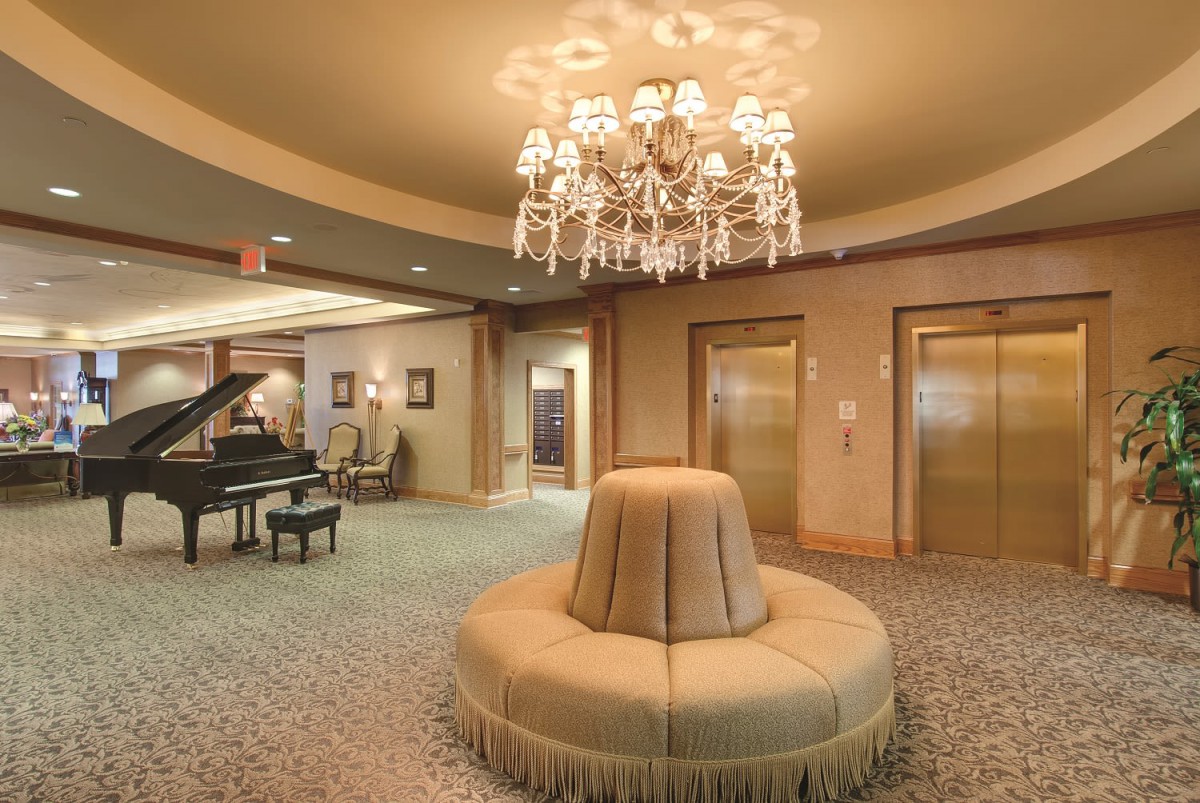 Elegant hotel lobby with chandeliers and a grand piano.