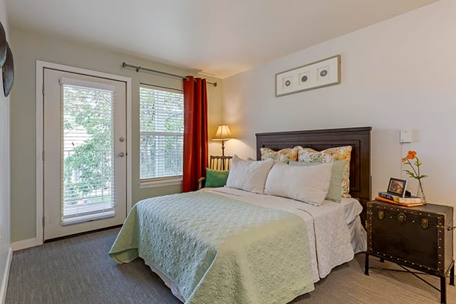 A cozy bedroom with a neatly made bed and natural light coming through the windows.