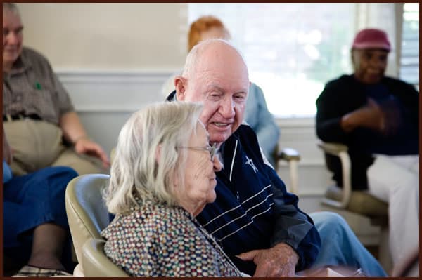 An elderly couple sitting closely together in a room, sharing a moment of companionship.