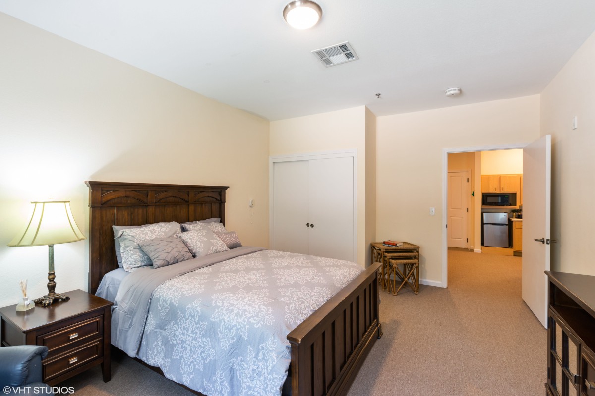 A cozy bedroom with a wooden bed frame and soft bedding.