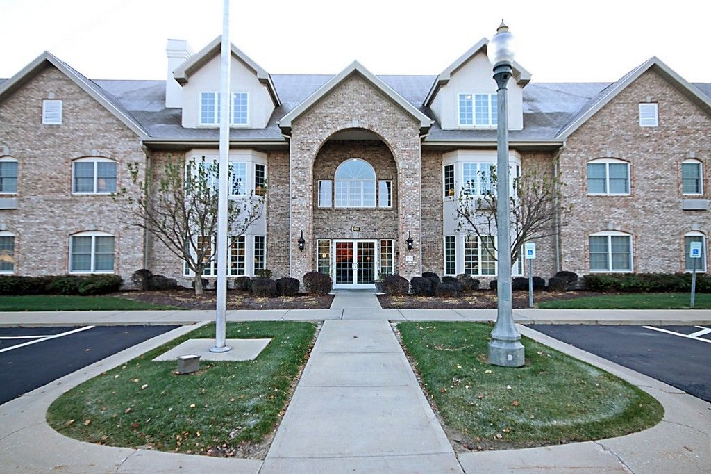 A large, symmetrical brick residential building with a central entrance and a well-maintained lawn.
