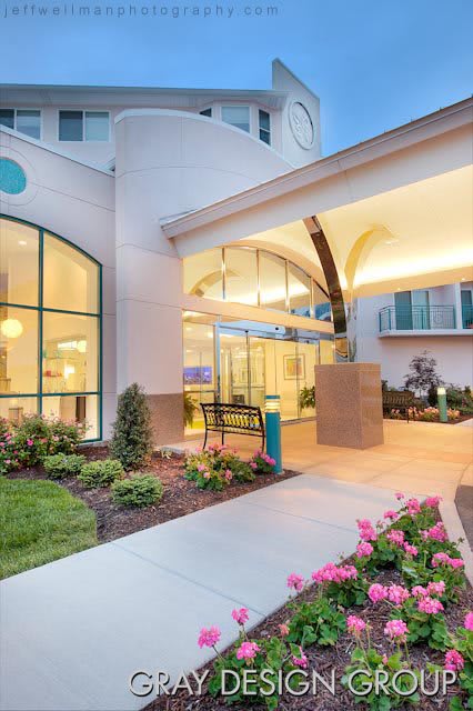 A well-lit hotel entrance with modern architecture and landscaped surroundings during the evening.