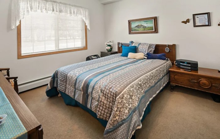 A cozy bedroom with a neatly made bed, featuring patterned bedding and decorative pillows.
