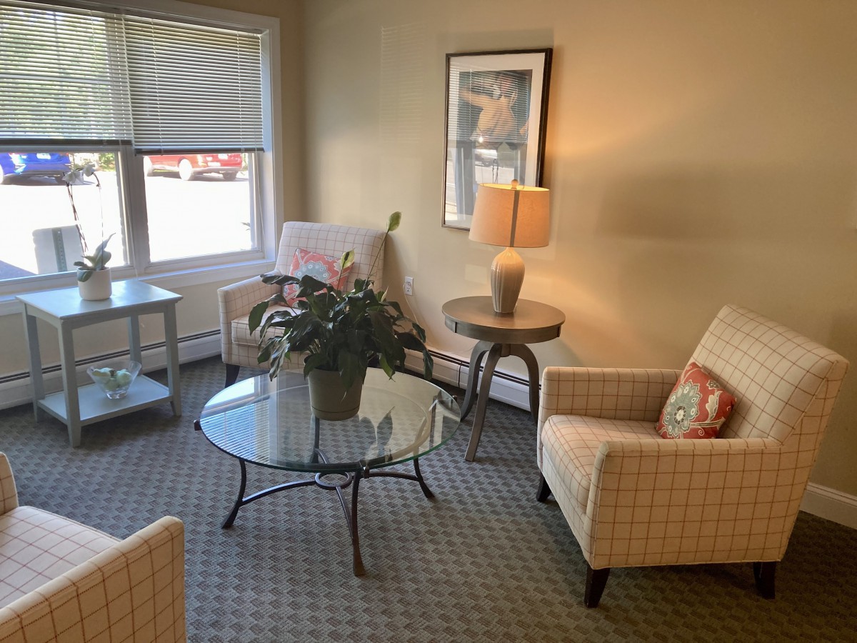 A cozy living room setup with armchairs, a glass coffee table, and a lamp.