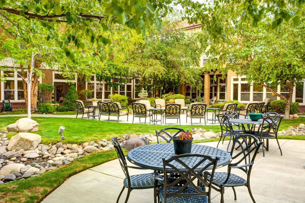 A serene outdoor patio area with tables and chairs surrounded by lush greenery.