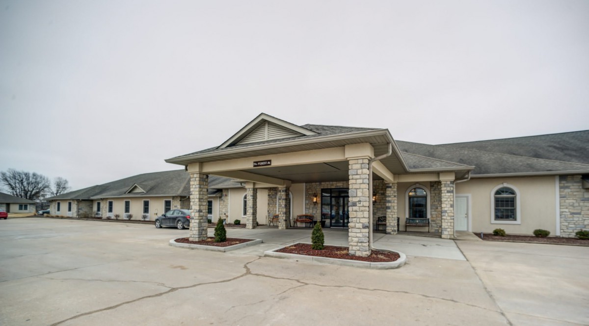 A facility building with a covered entrance and stone facade.