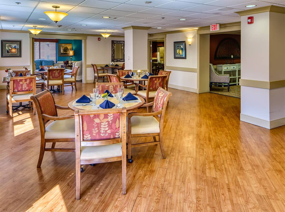 A well-arranged dining area with round tables, chairs, and neatly placed napkins.
