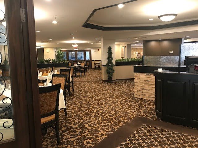 A spacious restaurant interior with elegantly set tables, warm lighting, and stylish decor.