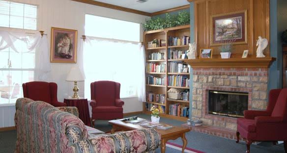 A cozy living room with a bookshelf, armchair, and fireplace.