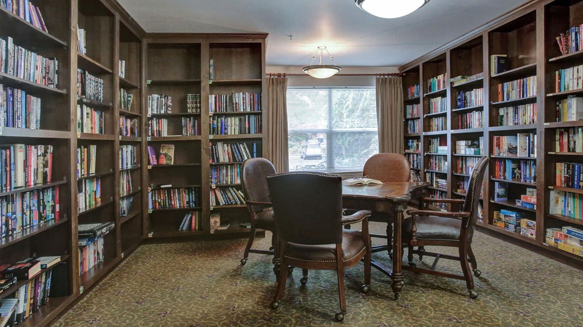 A cozy library reading nook with bookshelves, a table, and chairs.