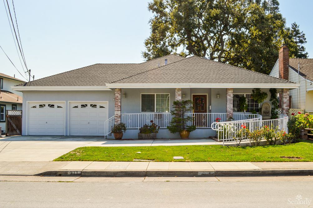 A suburban single-story house with a well-maintained front yard and a spacious porch.