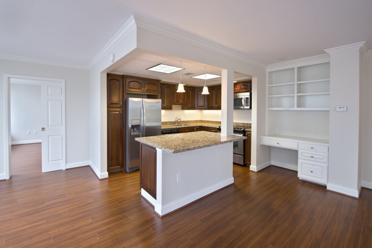 A modern kitchen featuring wooden flooring, a central island, and stainless steel appliances.