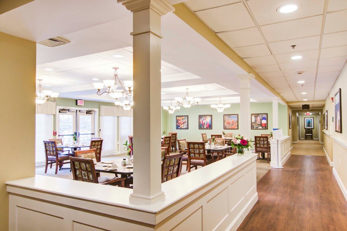 A well-lit dining area with elegant chandeliers and neatly arranged tables.