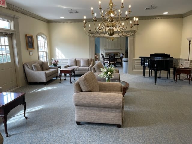 A spacious living area featuring elegant sofas, a grand chandelier, and a grand piano.