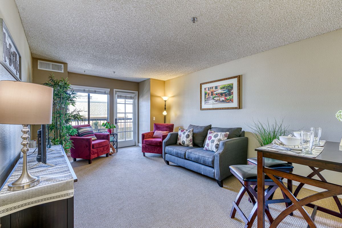 A cozy living room with a sofa, armchairs, and decorative elements like indoor plants and artwork.