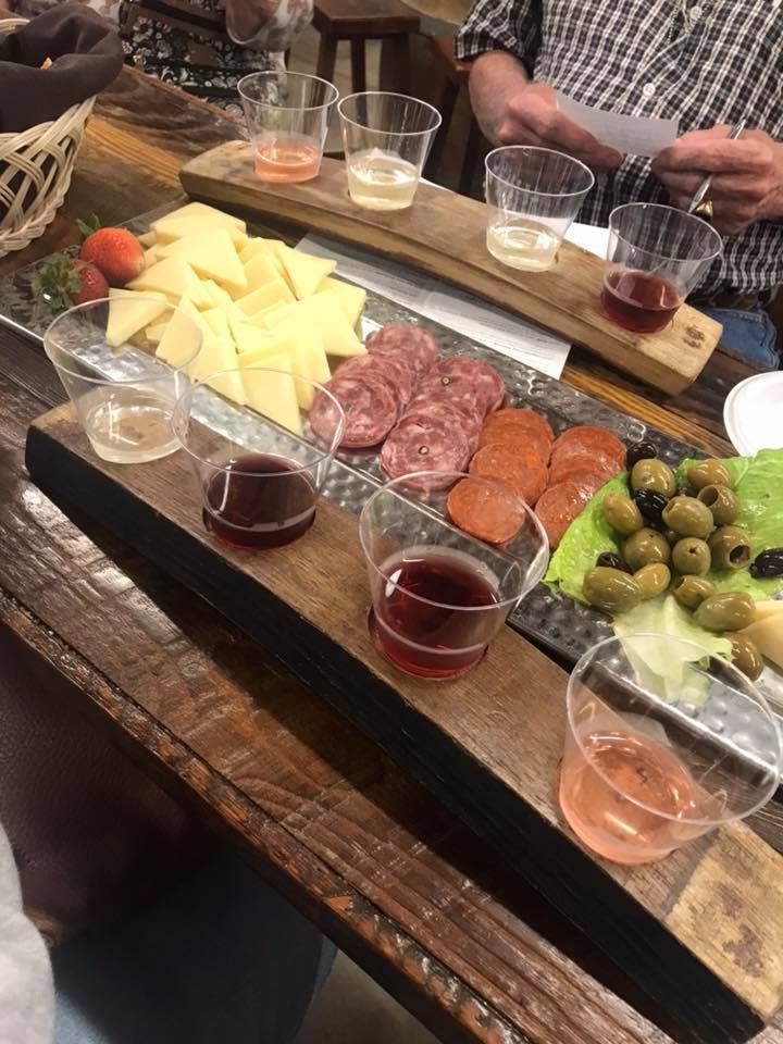 A beautifully arranged charcuterie board featuring cheese, meats, olives, and a selection of wines for tasting.