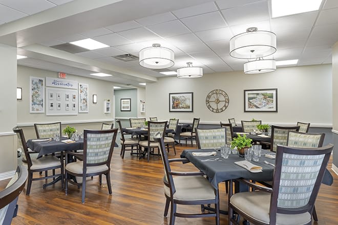 A well-lit dining room with neatly arranged tables and chairs, featuring modern decor and artwork on the walls.