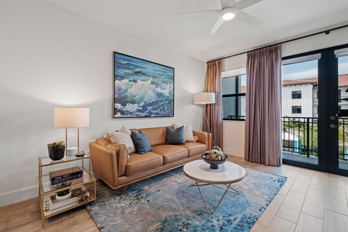 A modern living room featuring a brown leather sofa, a round coffee table, and vibrant artwork on the wall.