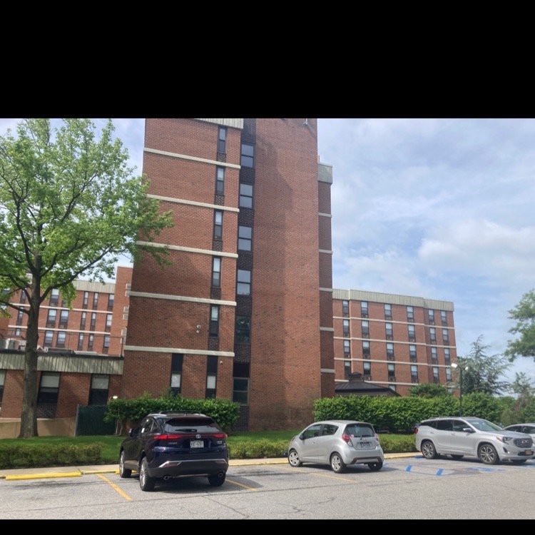 A view of a multi-story residential building with a parking lot in the foreground.