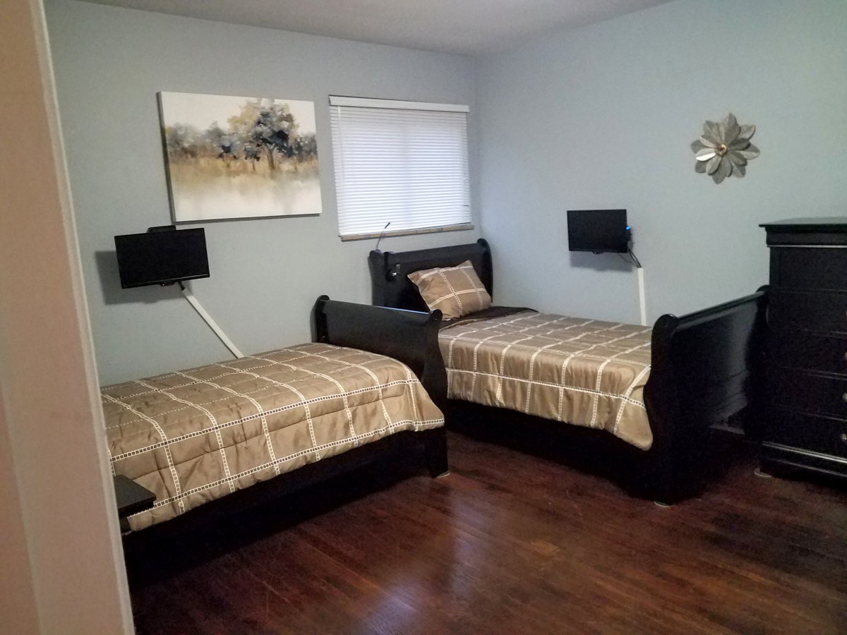 A modern bedroom with twin beds, featuring stylish bedding and wall art.