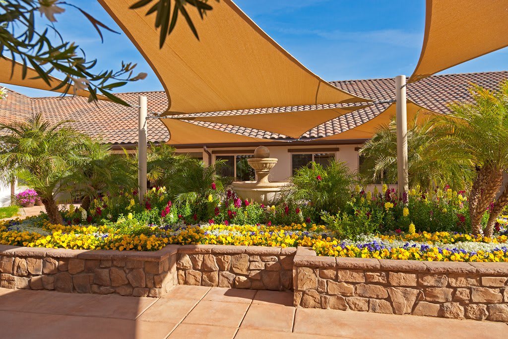 A beautifully landscaped garden with vibrant flowers and shade sails on a sunny day.
