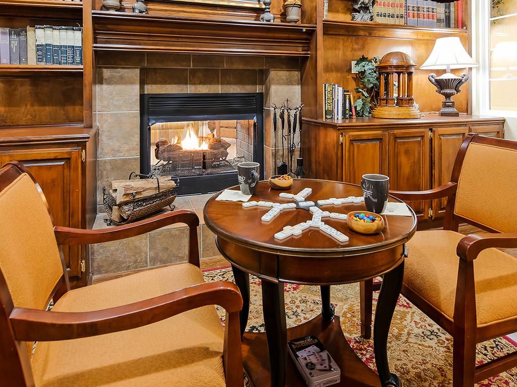 A cozy library setting featuring a fireplace, wooden furniture, and a table with dominoes.
