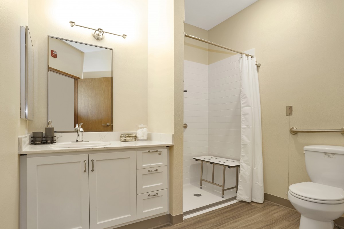 A modern, minimalist bathroom with a walk-in shower and white cabinetry.