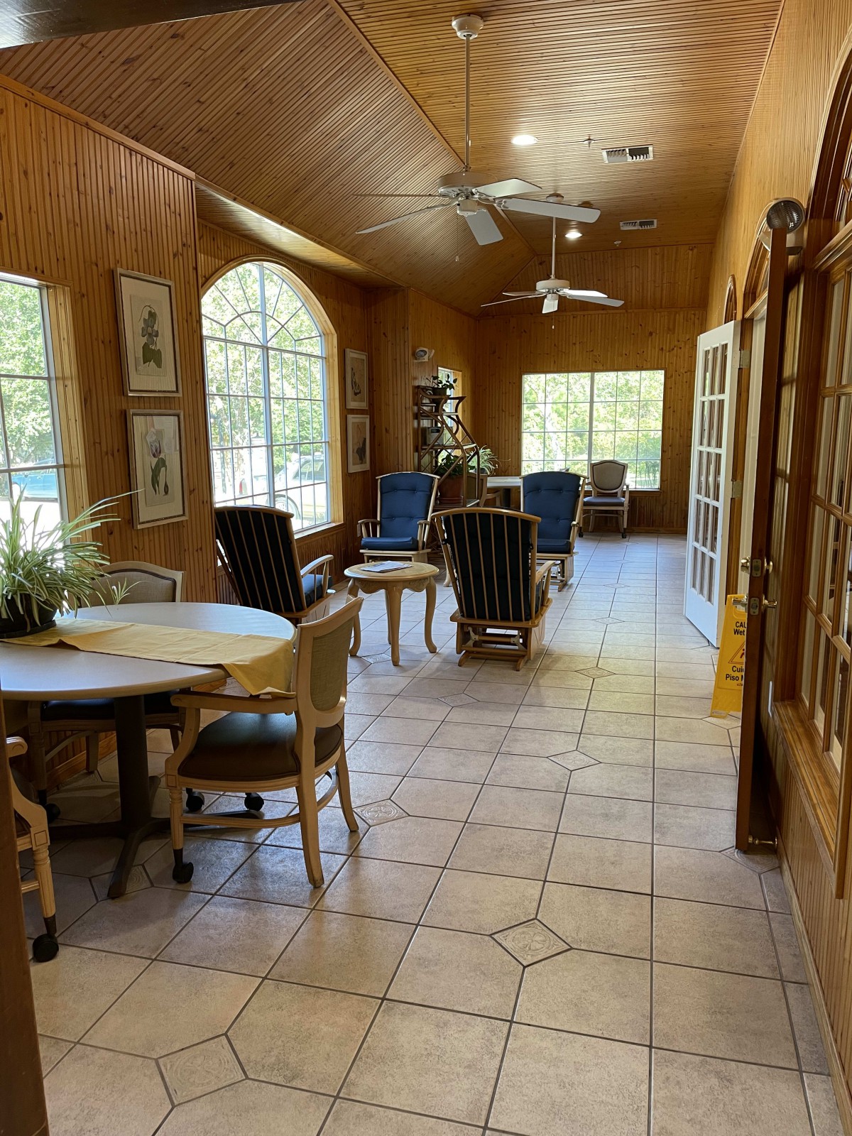 A sunlit room with various seating arrangements and large windows.
