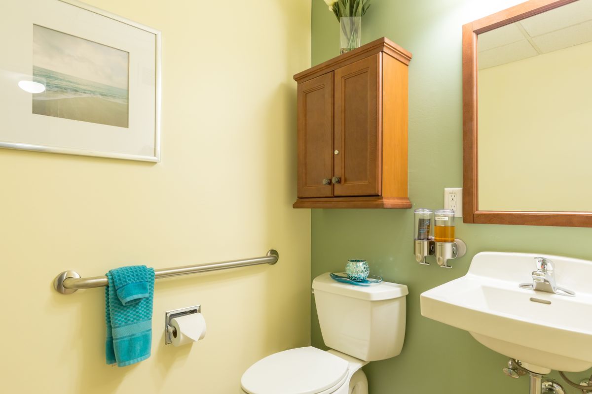 A neatly organized bathroom with a wooden cabinet and green accents.
