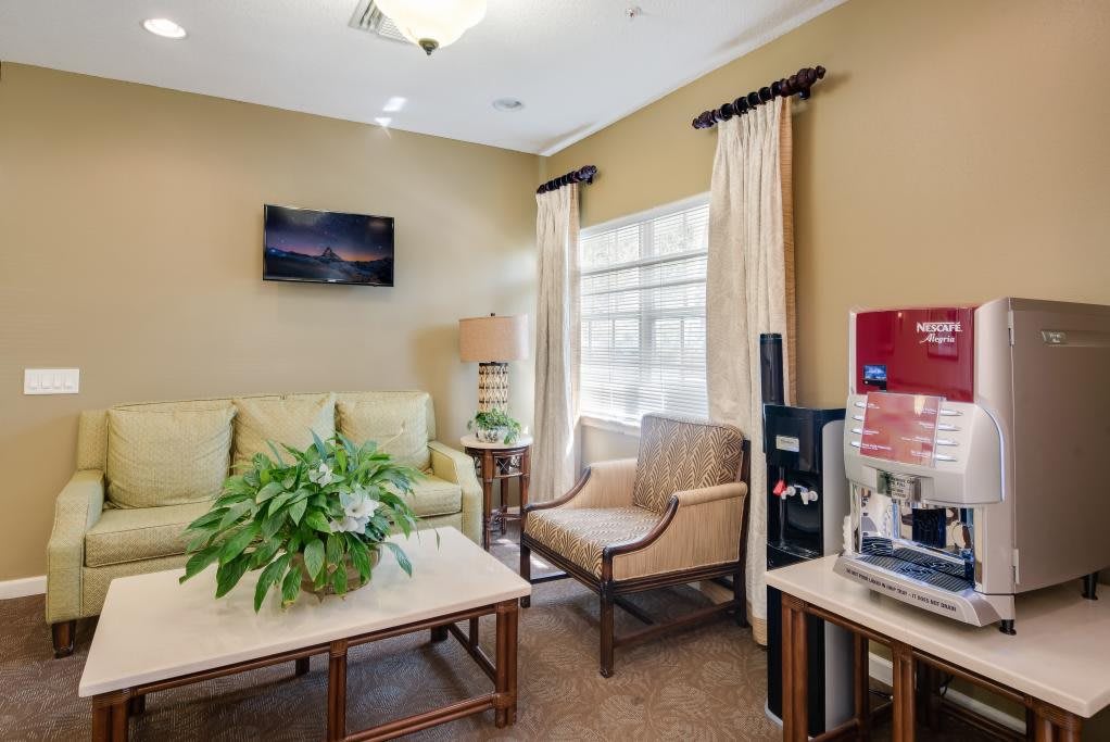 A cozy waiting room with comfortable seating, a television, and a coffee machine.