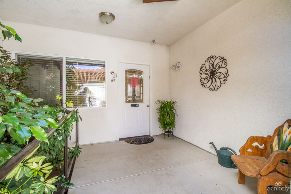 A cozy indoor patio space with plants, a decorative wall piece, and a door leading outside.