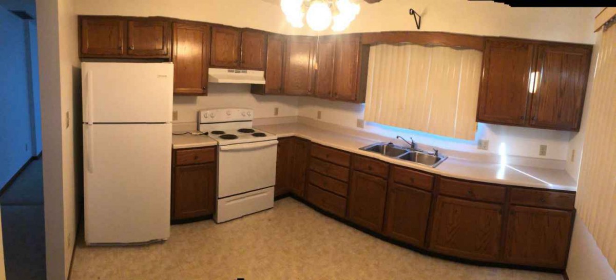 A cozy kitchen featuring wooden cabinets, a stove, and a sink.