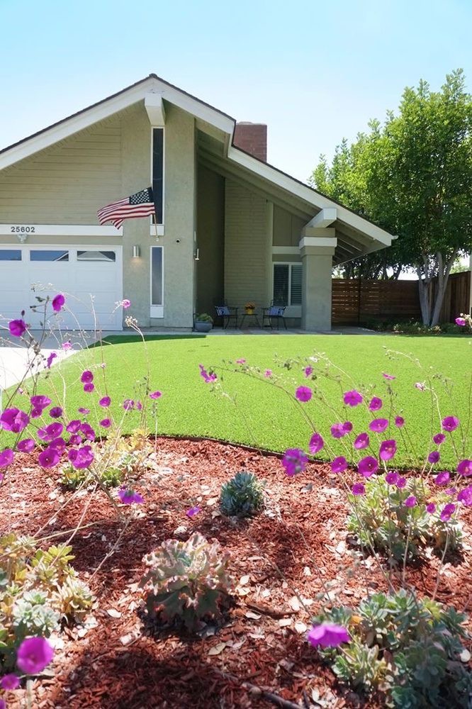 A suburban house with a well-maintained lawn and vibrant flower garden.