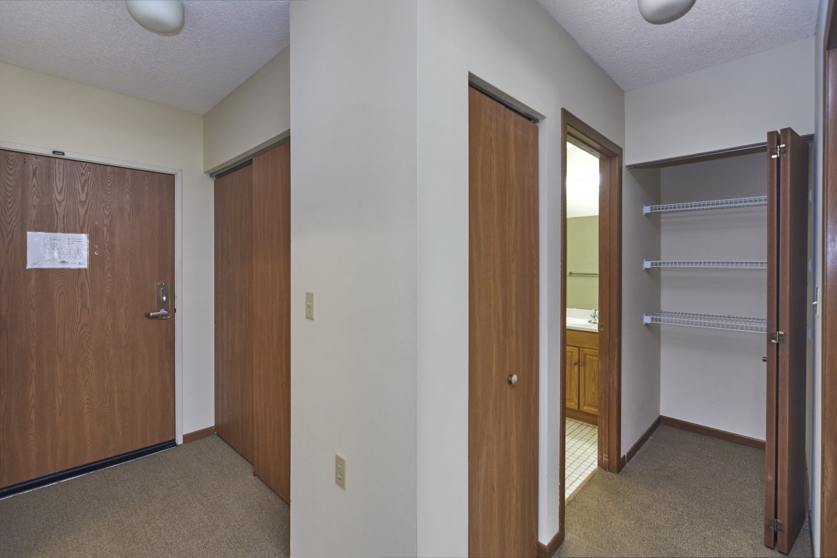 A hallway with multiple wooden doors, including a closet and bathroom entrance.