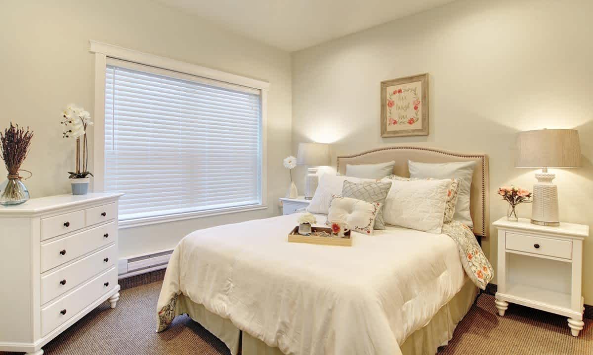 A cozy and elegantly decorated bedroom with neutral tones and soft lighting.