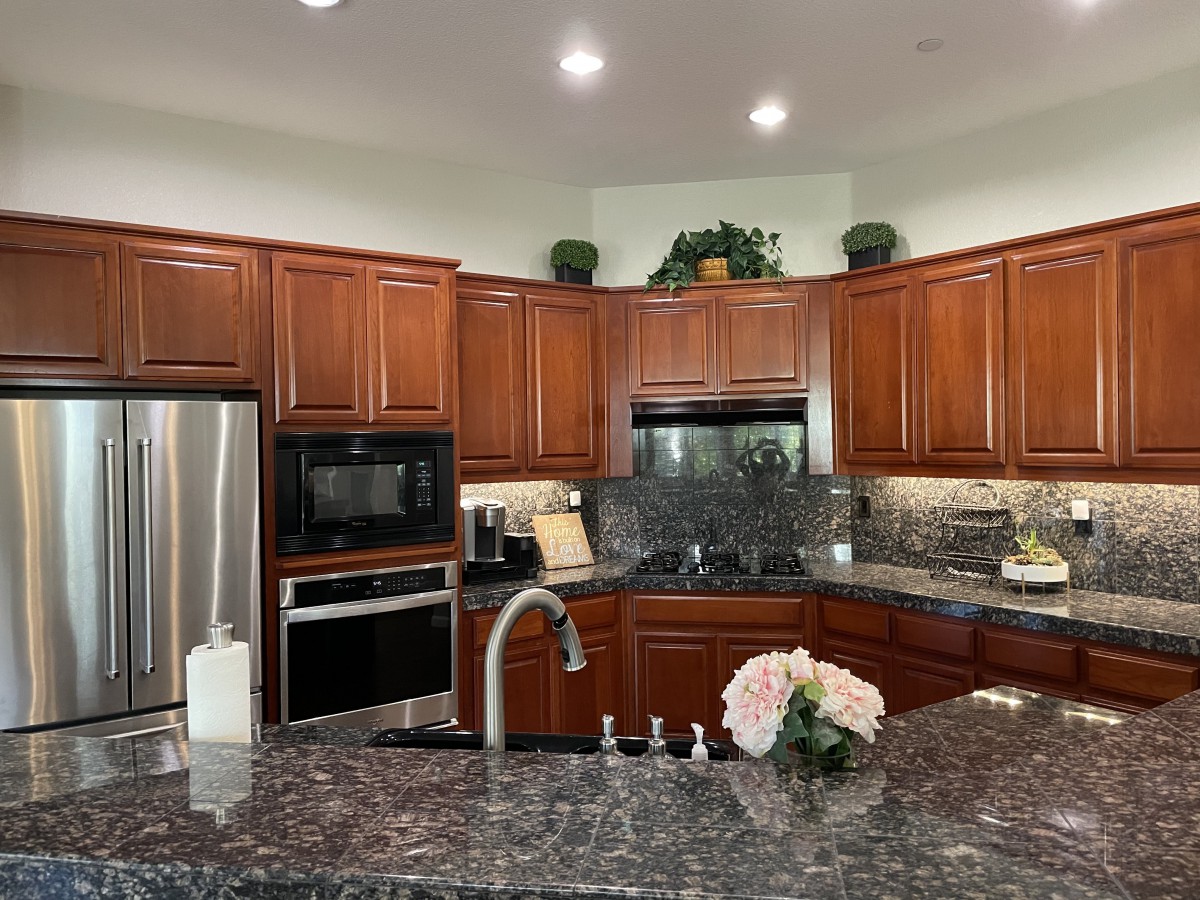 A modern kitchen with wood cabinets, granite countertops, and stainless steel appliances.