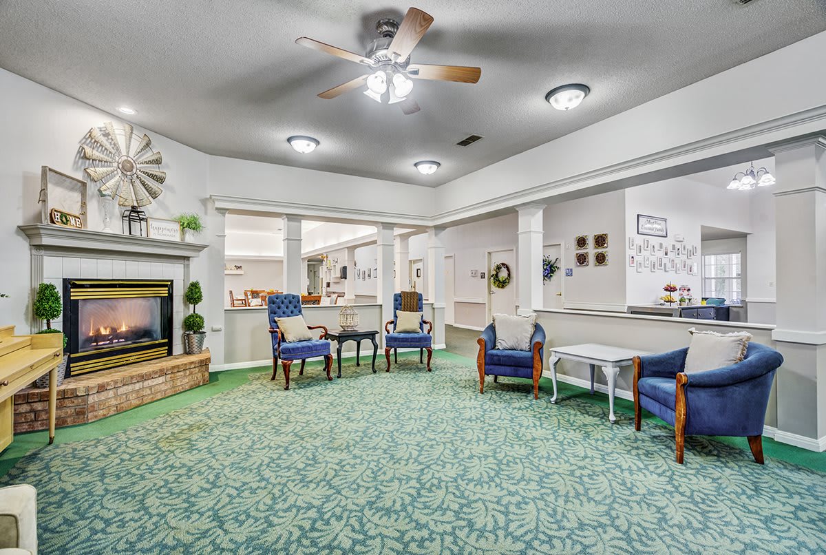 A cozy and spacious living room with a fireplace, ceiling fan, and comfortable seating.