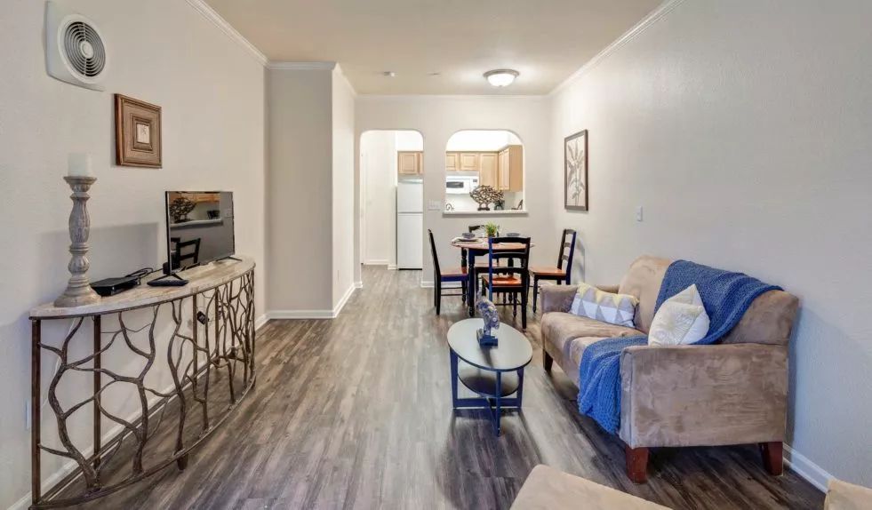 A modern apartment living room with an open kitchen and dining area.