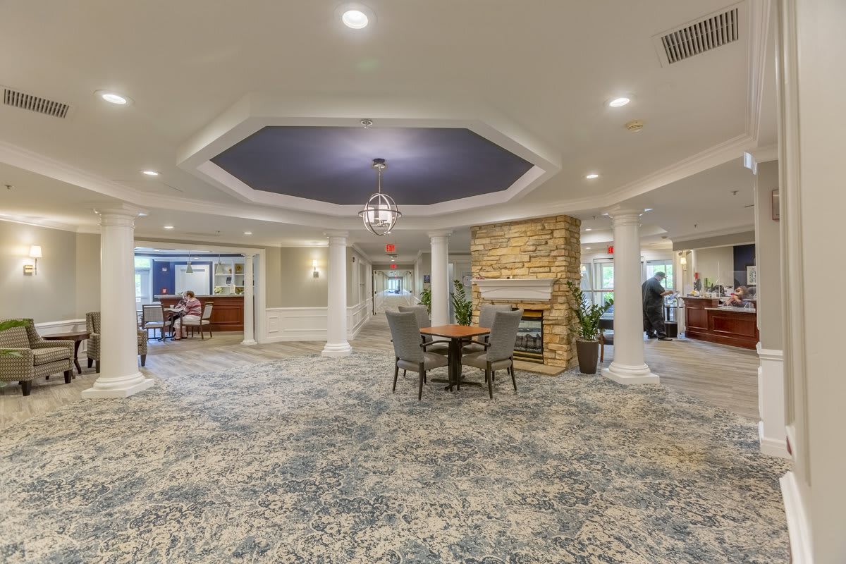 A spacious lobby featuring a cozy seating area with a fireplace, elegant columns, and modern ceiling lights.