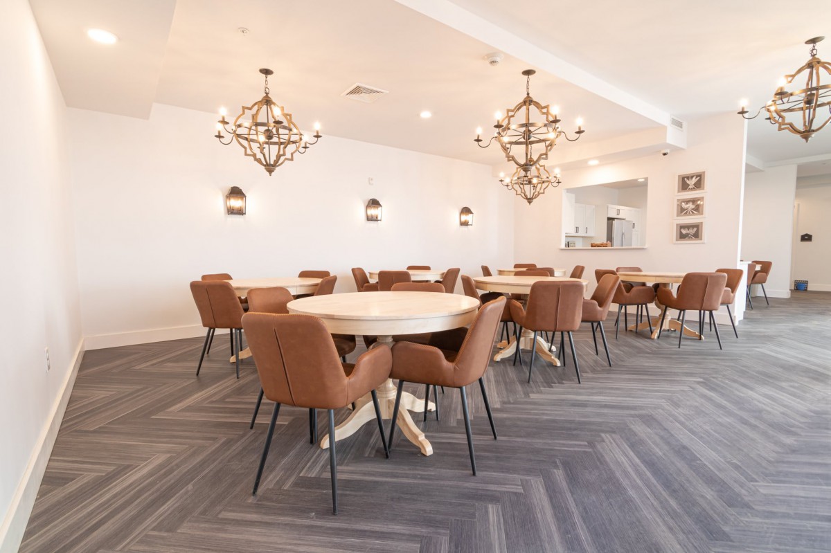 A modern dining area with elegant chandeliers, round tables, and comfortable chairs.