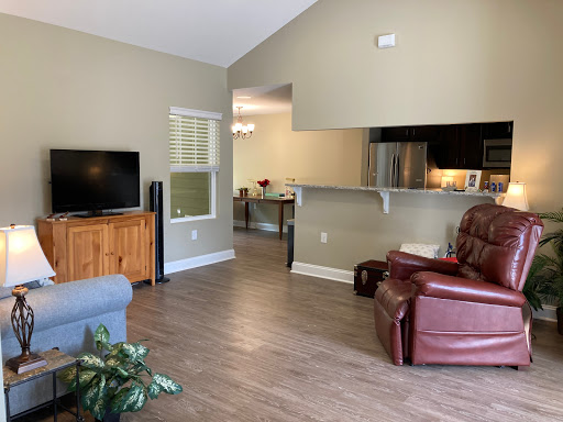 A cozy living room featuring a television, a comfortable sofa, and a recliner, with an open layout connecting to the kitchen.