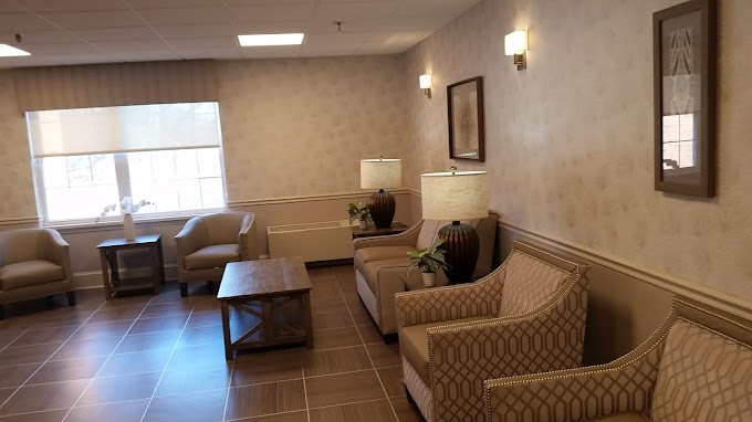 A cozy seating area with chairs, a sofa, and a table complemented by warm lighting.