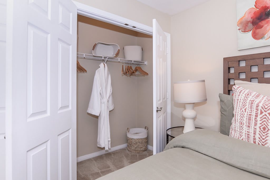 A cozy bedroom with an open closet featuring a hanging bathrobe and storage baskets.