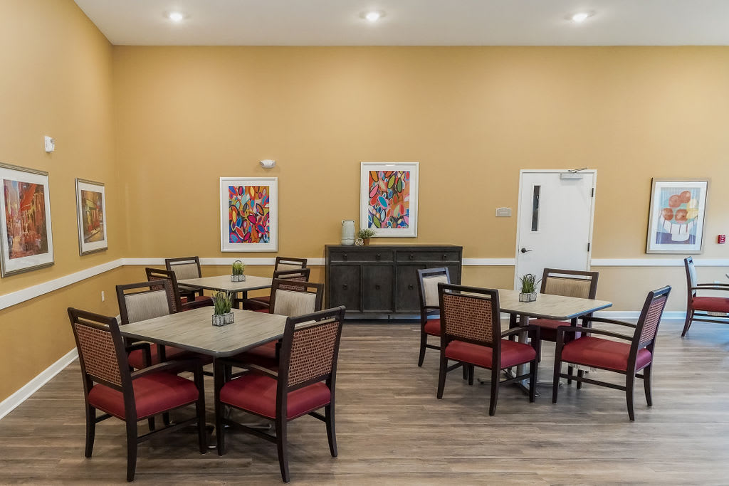 A tidy dining area with neatly arranged tables and chairs, decorated with colorful artwork on the walls.