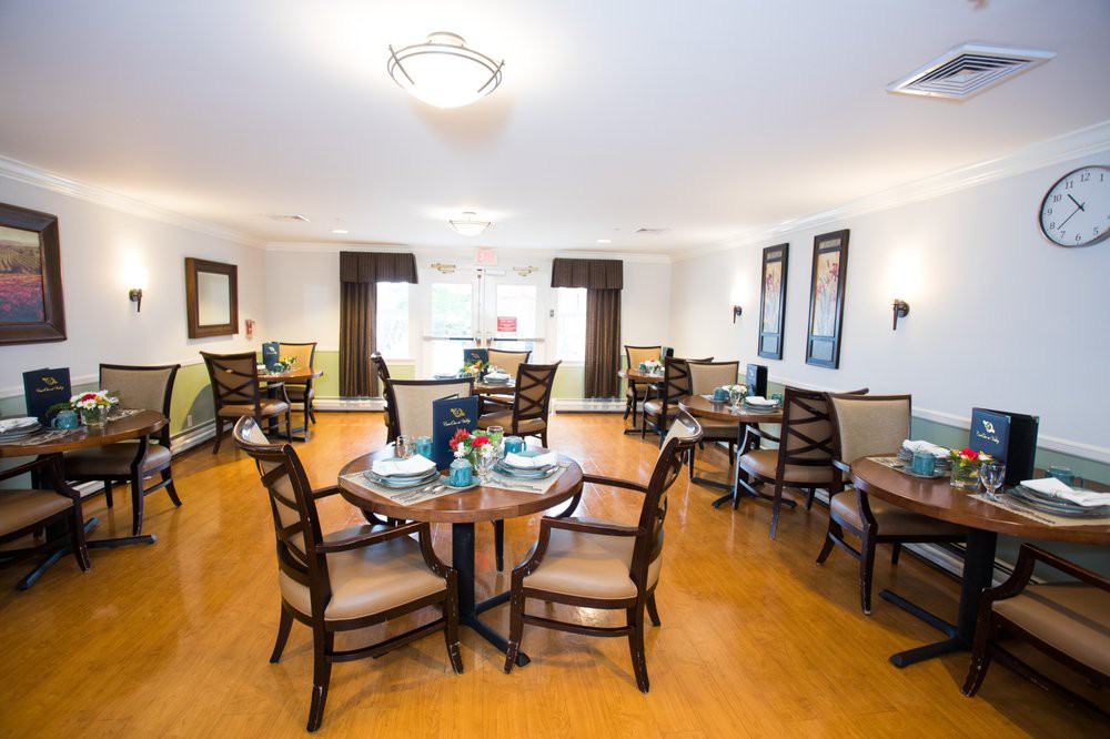 A spacious dining area with several round tables and chairs, featuring a well-lit interior and hardwood floors.