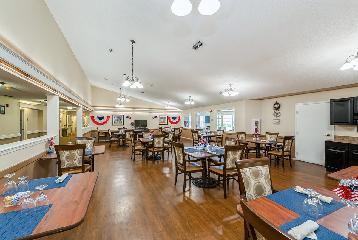 A spacious dining room with neatly arranged tables and chairs, decorated with patriotic-themed banners.