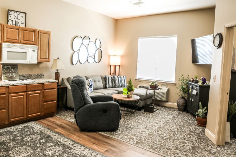 A cozy living room featuring a sofa, recliner, coffee table, and TV with tasteful decor including mirrors and lamps.