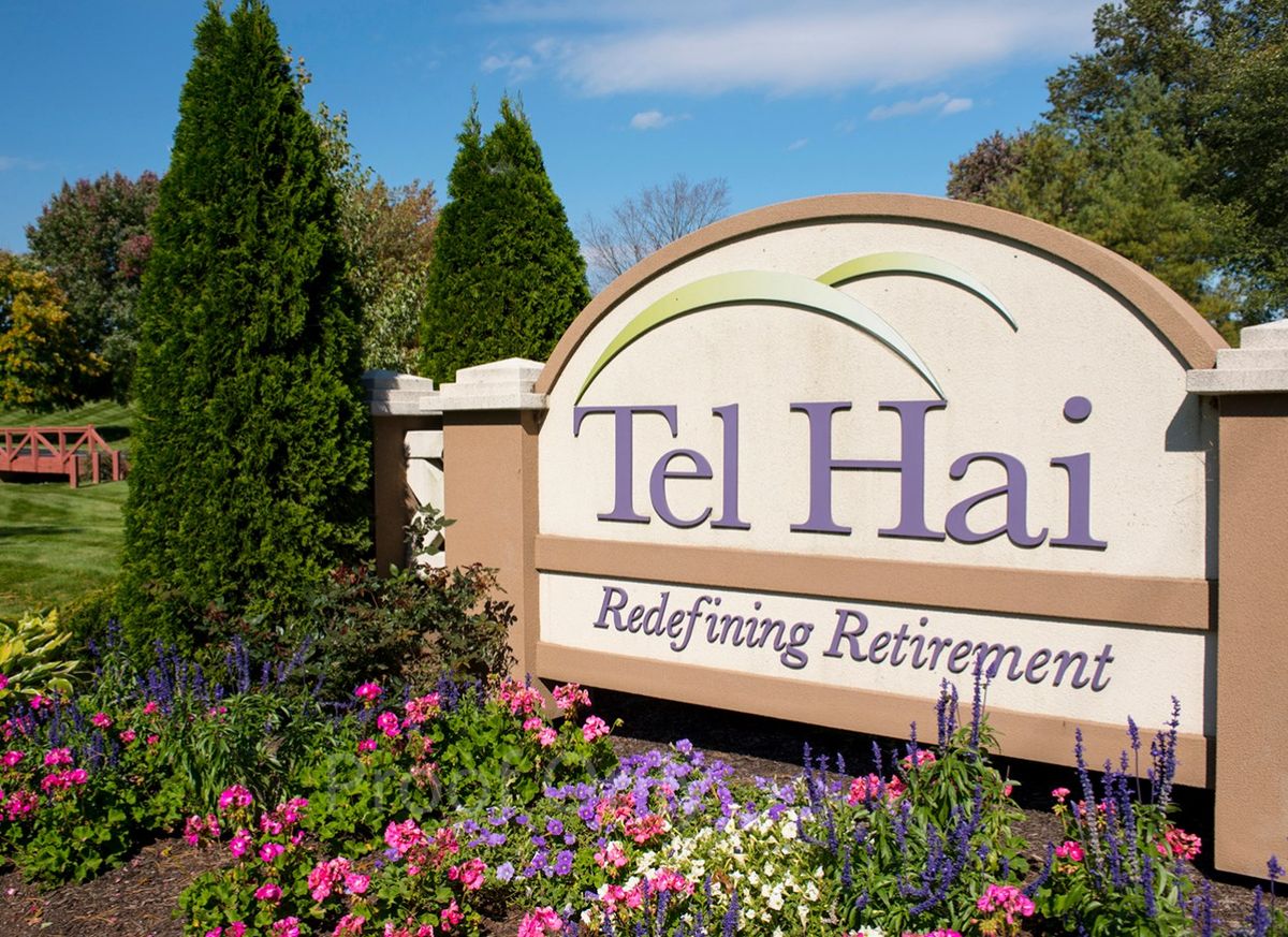 Entrance sign for Tel Hai, a retirement community, surrounded by colorful flowers and greenery.