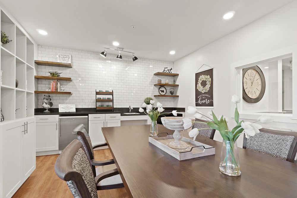 A modern kitchen and dining area featuring a wooden table, open shelving, and bright lighting.